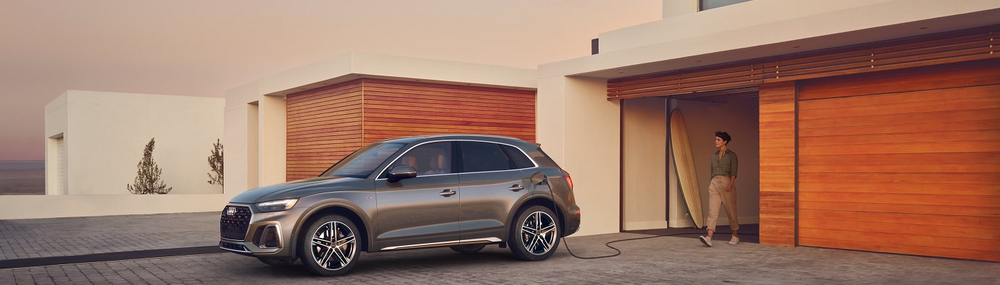 Grey Audi Q5 e charging by a beach house garage