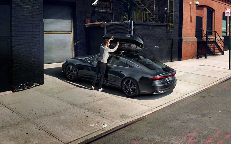 Man loading roof box on Audi sedan in the city