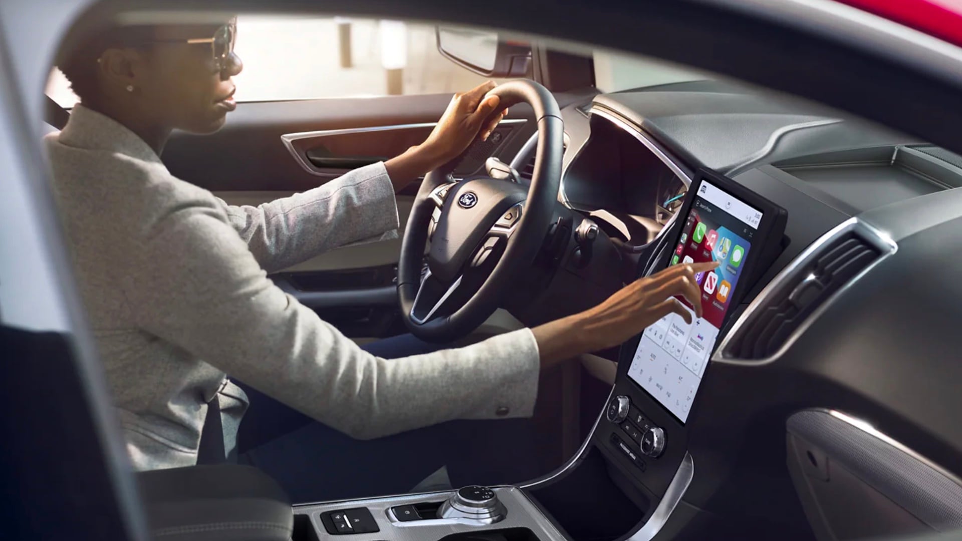 Learn about Apple CarPlay A woman sits in the driver's seat of a Ford using the touch screen displaying the Apple CarPlay interface