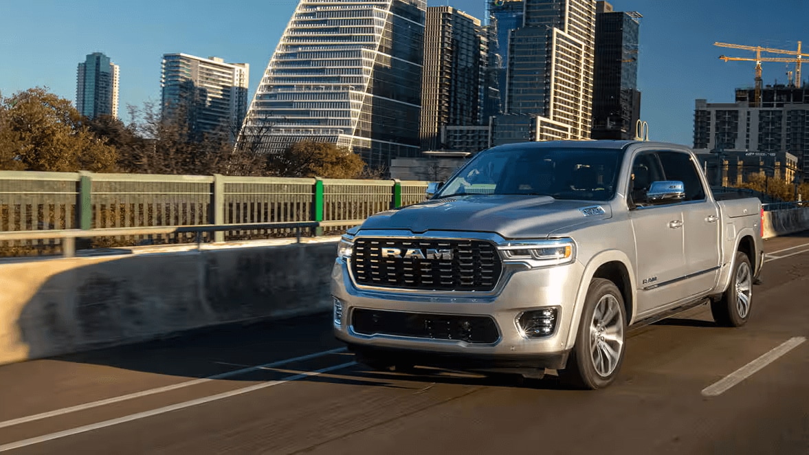 Action photo of a silver Ram 1500 driving down a city street