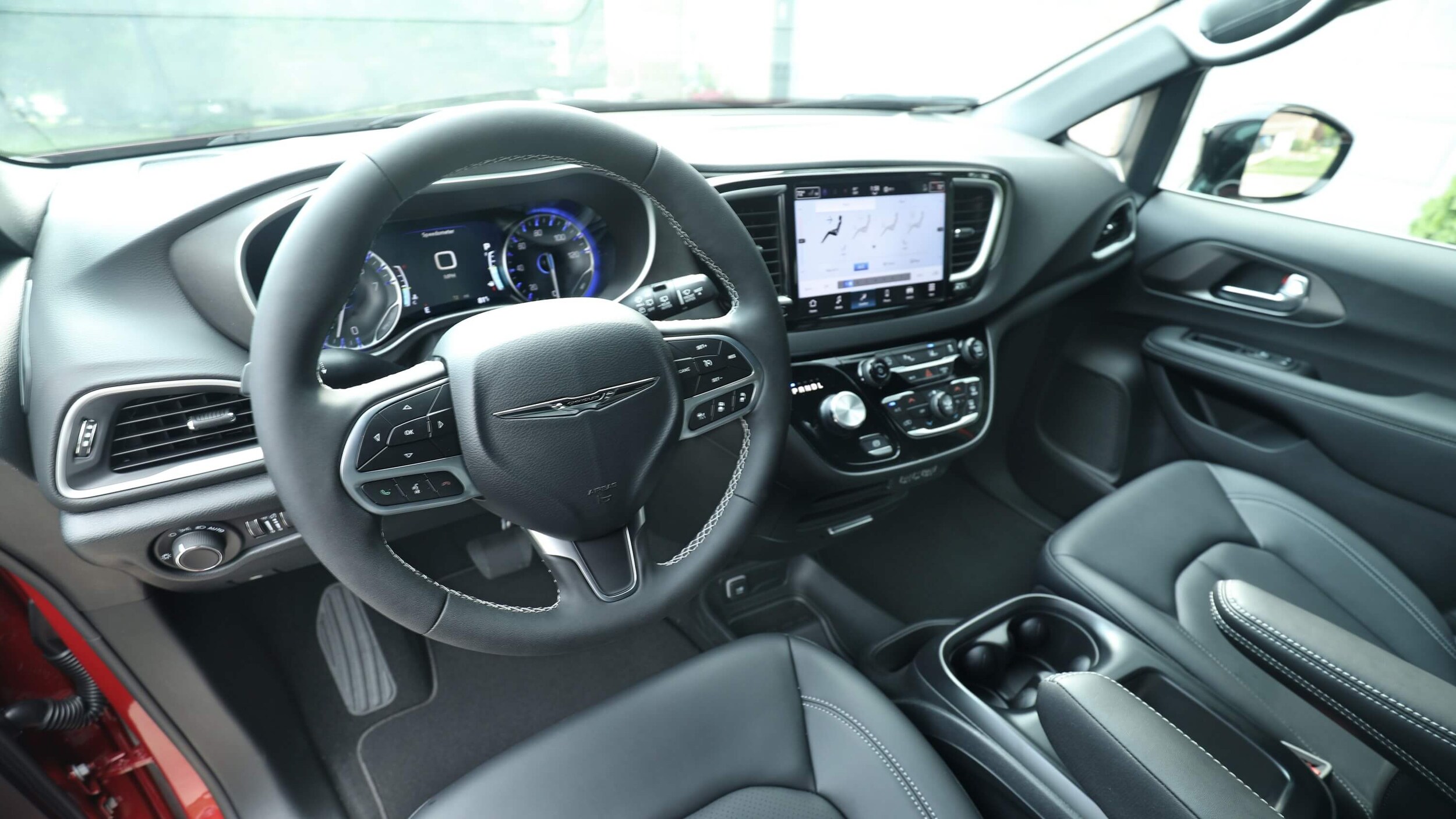 Learn about the technology features of the Chyrsler Voyager Interior shot of the Chrysler Voyager dashboard, showing the steering wheel, touchscreen, and digital gauge cluster