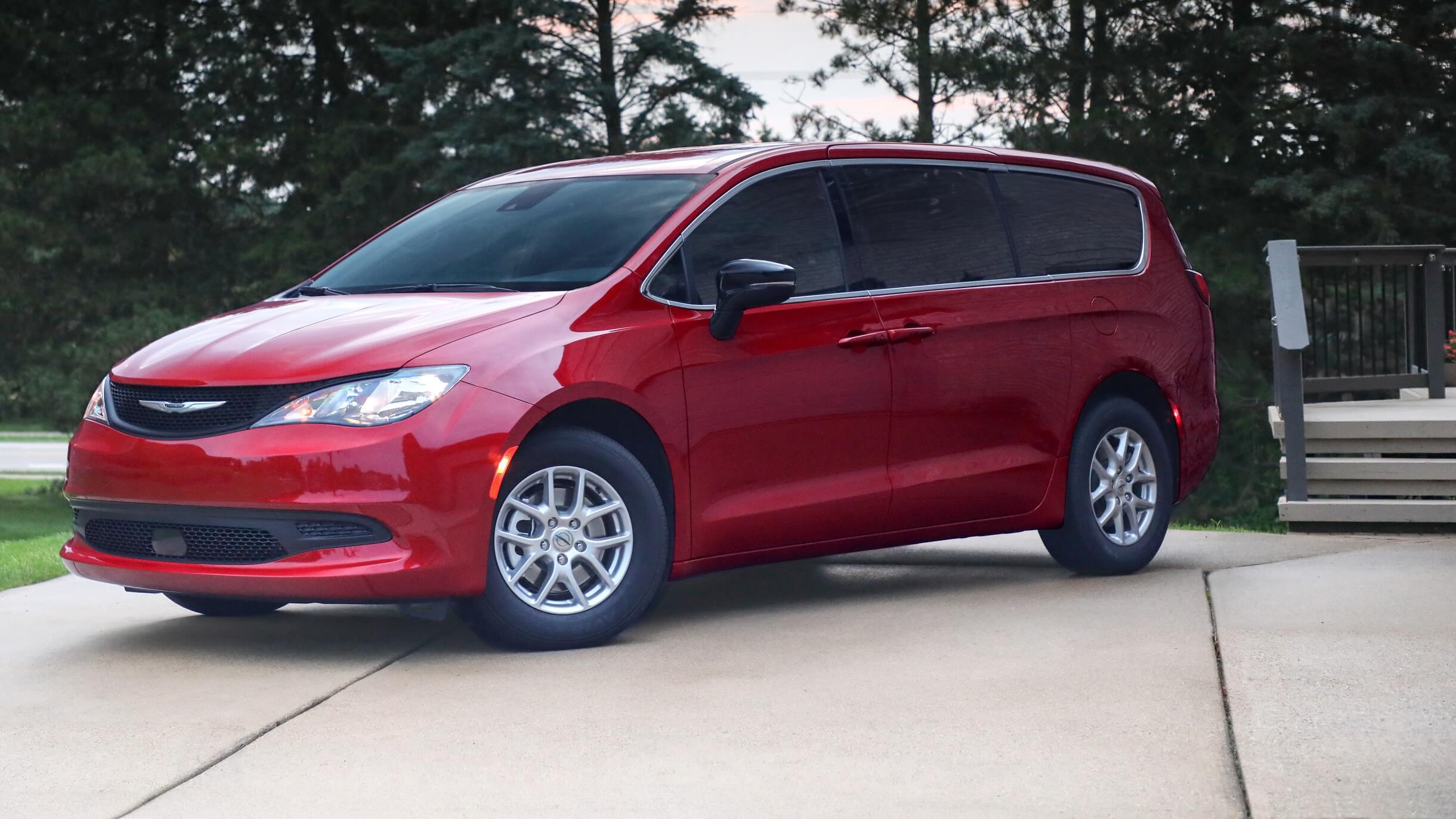 Outdoor shot of a red Chrysler Voyager parked outside a house