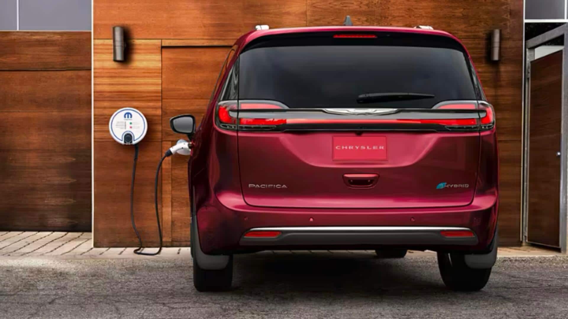 Chrysler Pacifica plugged in to charge outside of a wood paneled garage
