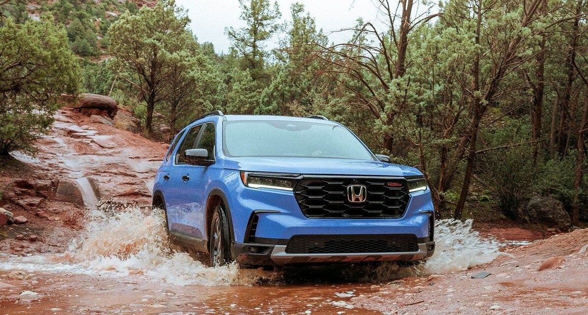 Honda Pilot TrailSport in Diffused Sky Blue Pearl Honda Pilot TrailSport in Diffused Sky Blue Pearl driving through water in a forested mountain surrounding.