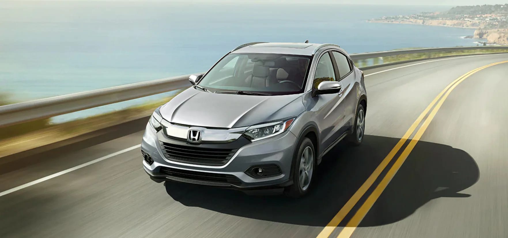 Silver Honda HR-V driving down a highway on a sunny day