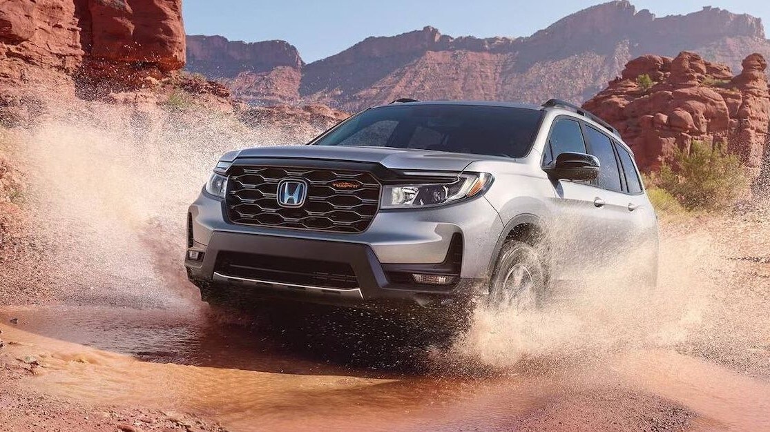 Honda Passport TrailSport in Lunar Silver Metallic driving through a puddle in a rocky desert surrounding.