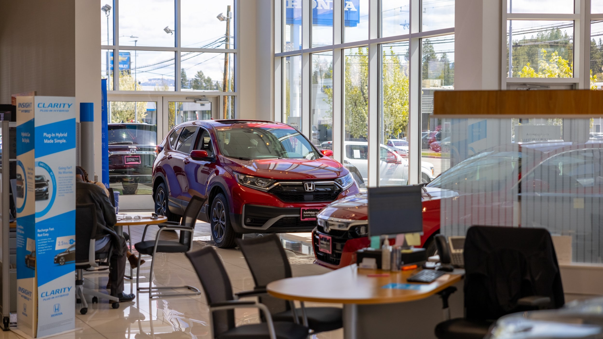Interior view of [Dealership 
Name]. Red Honda parked near round table with chairs