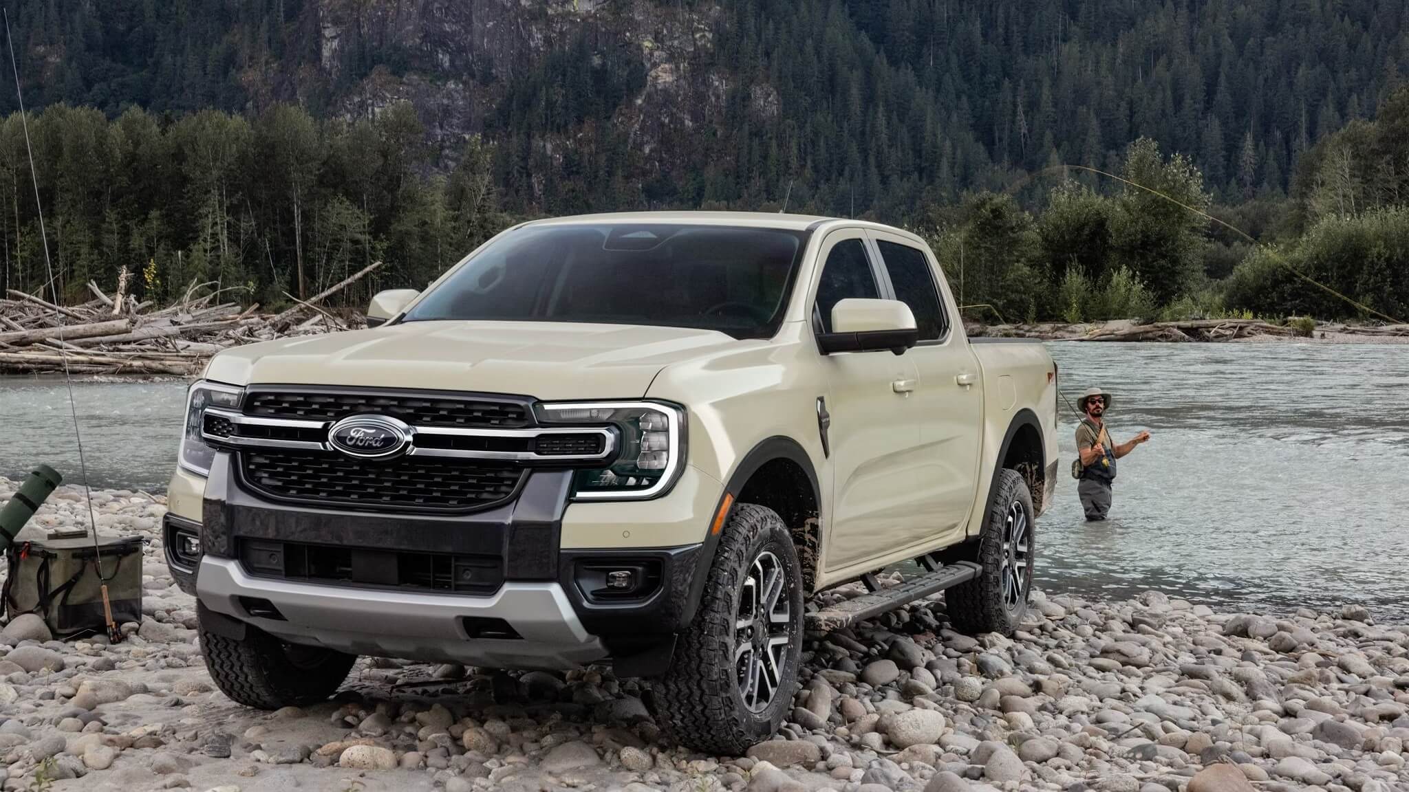 Exterior shot of a Ford Ranger parked next to a river with a man fishing in the background