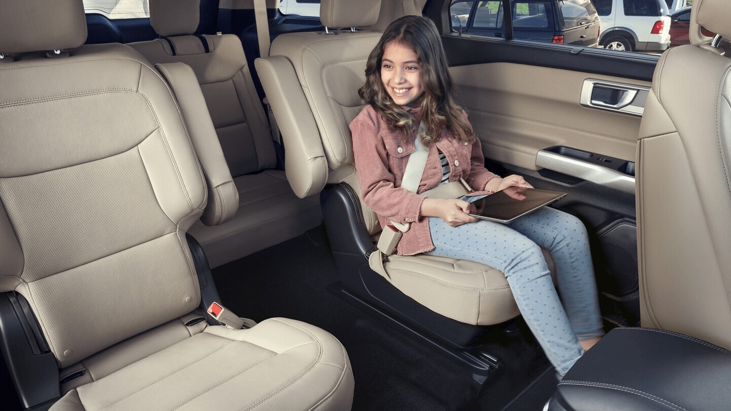 Interior shot of a Ford Explorer, showing the standard third row seating in the back. In the second row, a little girl occupies a second-row captain's chair while holding a tablet