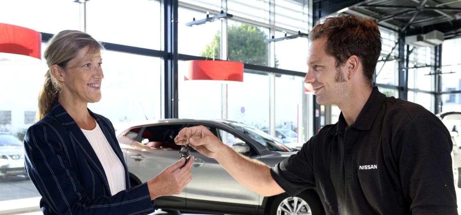 A Nissan Service Technician handing a set of car keys back to the owner.