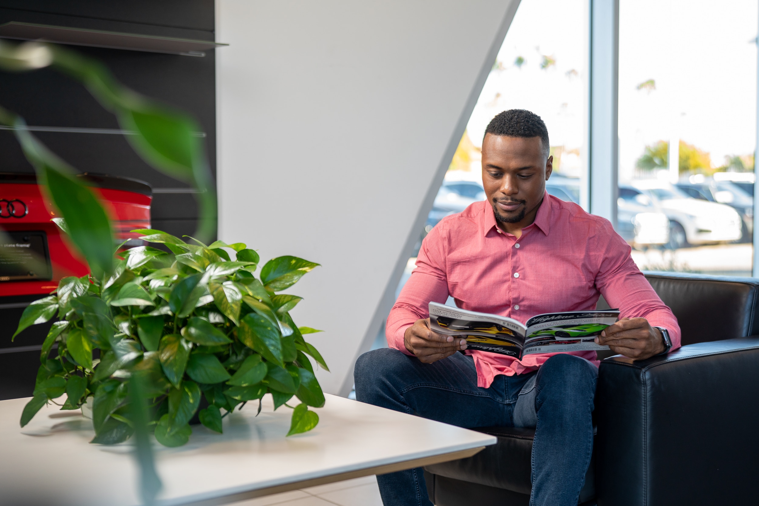 Man reads magazine in a chair while waiting for vehicle to be serviced