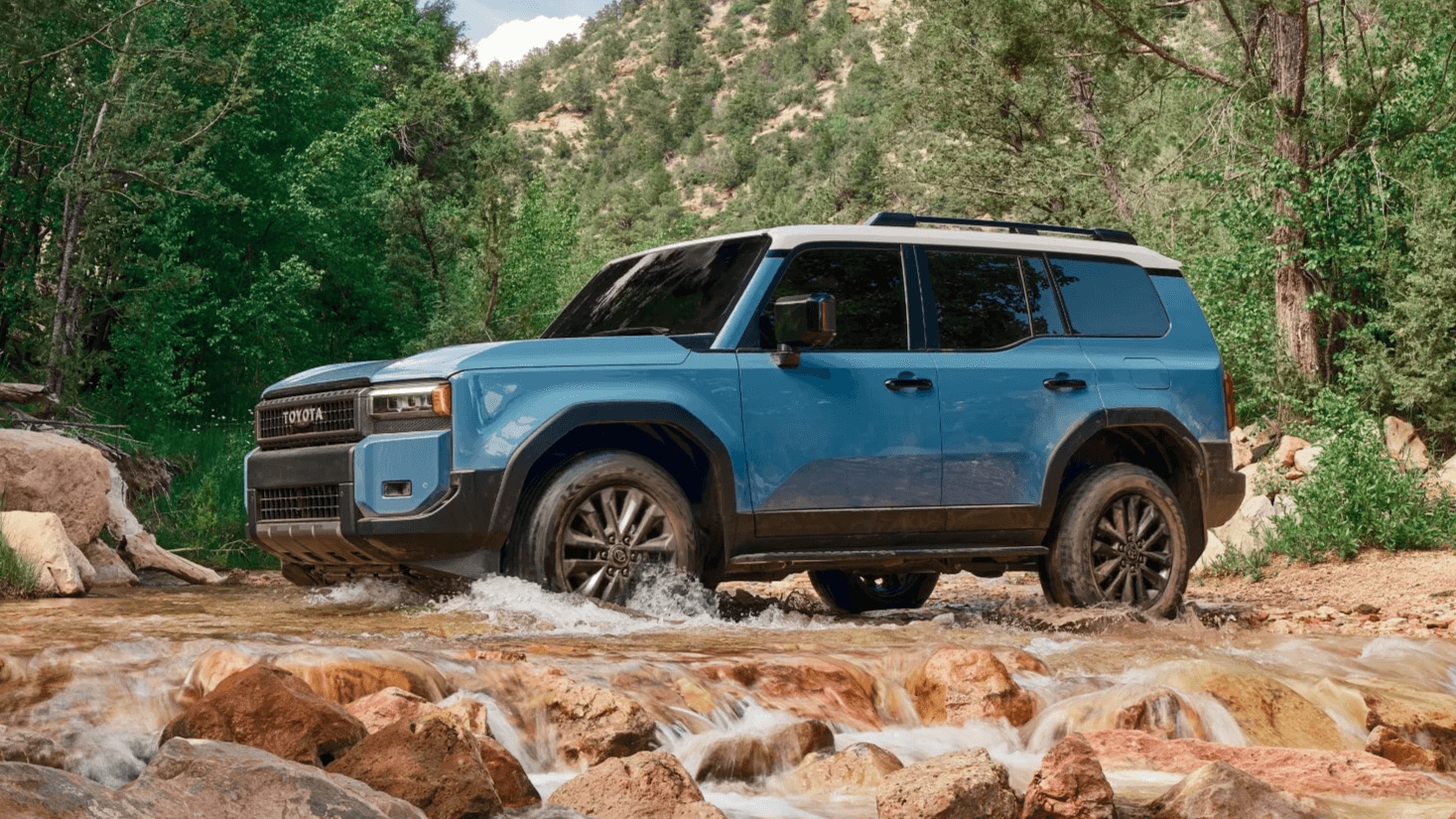 Learn about the performance features of the Toyota Land Cruiser Outdoor shot of a Toyota Land Cruiser traveling across a stream in the woods