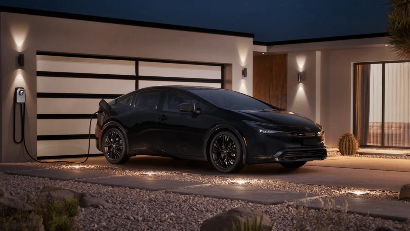 Toyota Prius parked outside at a residence with the plug-in charger connected to the charging station attached to a garage