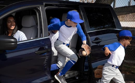Kids in baseball uniforms getting out of a van