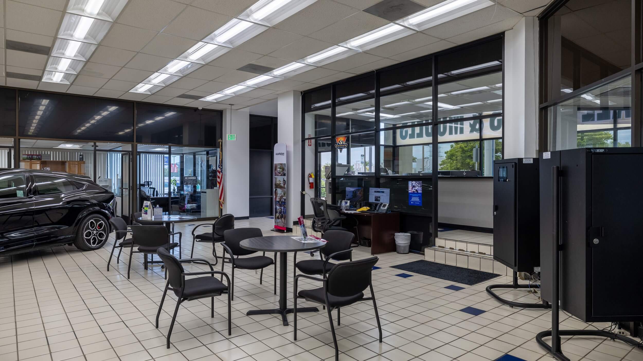 AutoNation Ford Valencia Interior of AutoNation Ford dealership in Valencia, CA showing an office desk, tables, chairs, and a vehicle on display