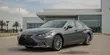 Pre-owned Lexus ES sedan parked outside a modern dealership in Plano, Texas