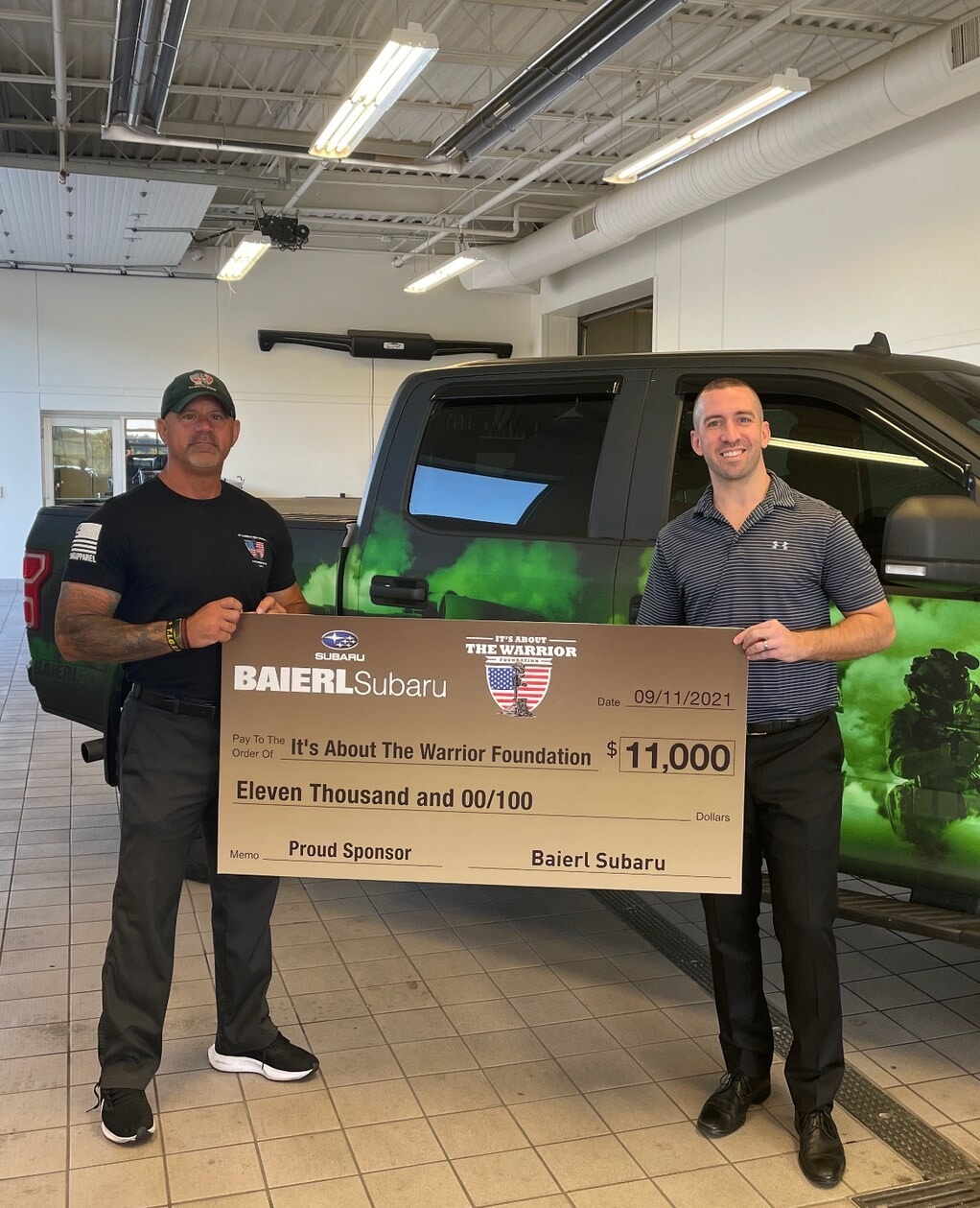 Baierl Subaru staff member with a charitable donation check for the Wounded Warriors Foundation