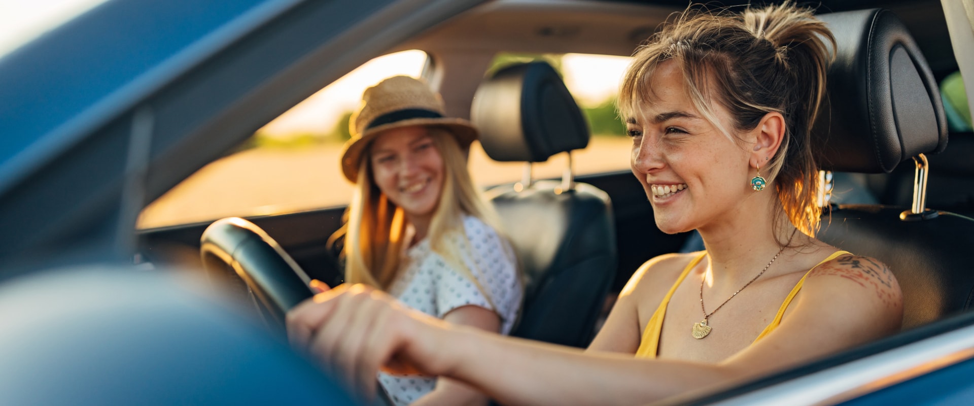 A young driver and her friend driving their new car enjoying the ride