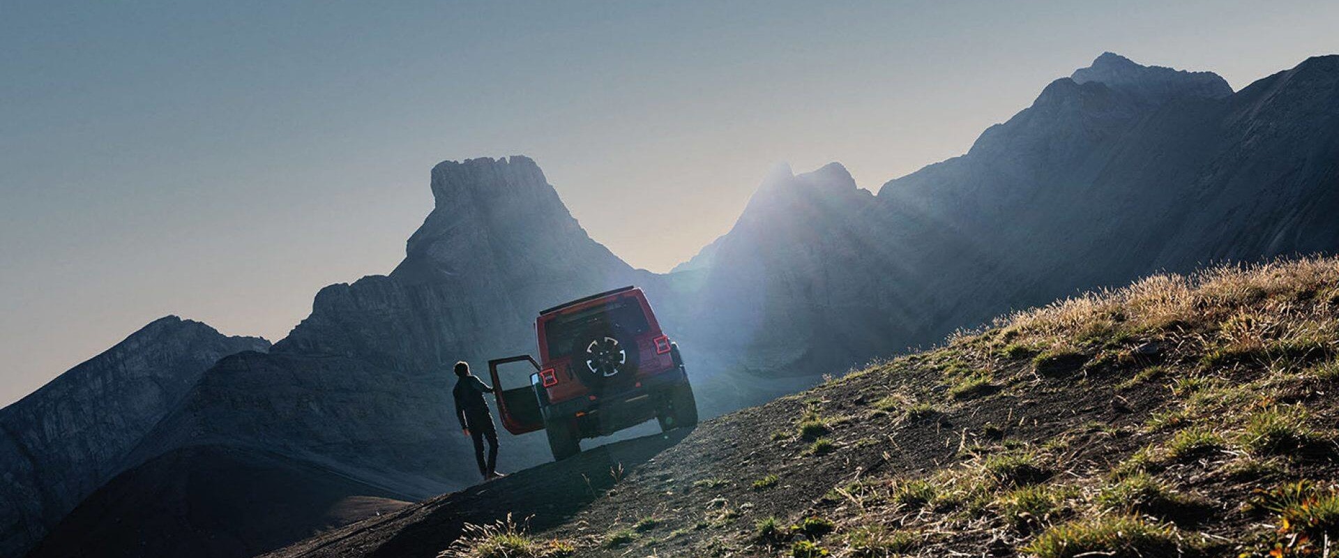 Man standing next to the 2026 Jeep Wrangler looking at the sunset