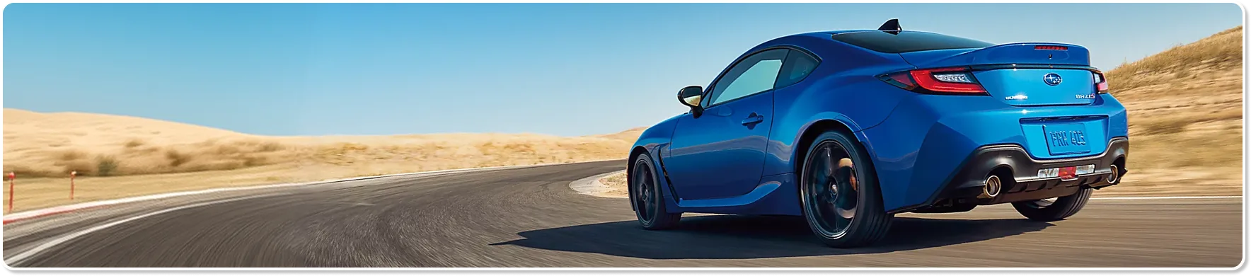 A blue Subaru BRZ carving through a coastal curve