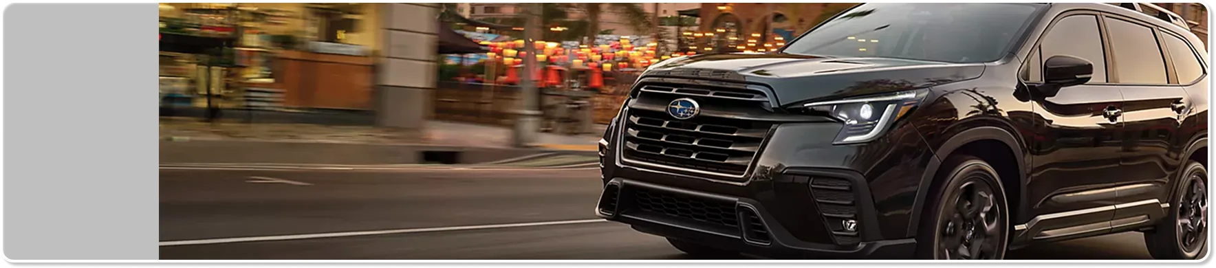 A dark 2026 Subaru Ascent parked on a tree-lined suburban street at dusk