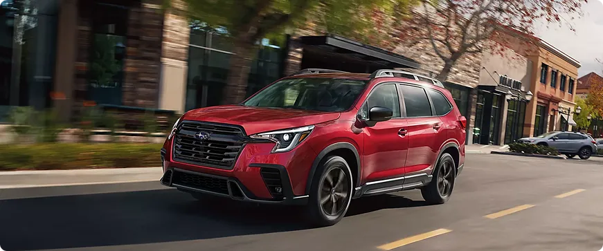 A red Subaru Ascent moving along a downtown street
