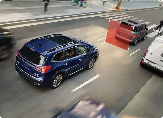 A blue Subaru Ascent braking behind a truck in city traffic