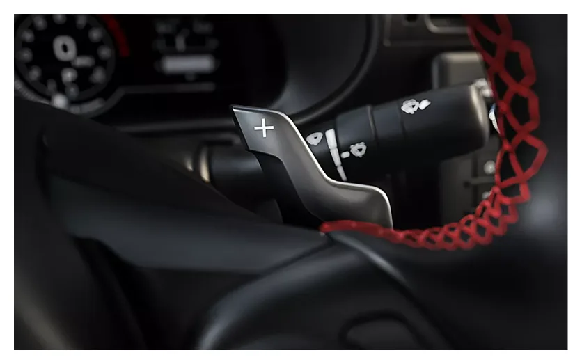 Close-up of a steering-wheel paddle shifter with red accent trim