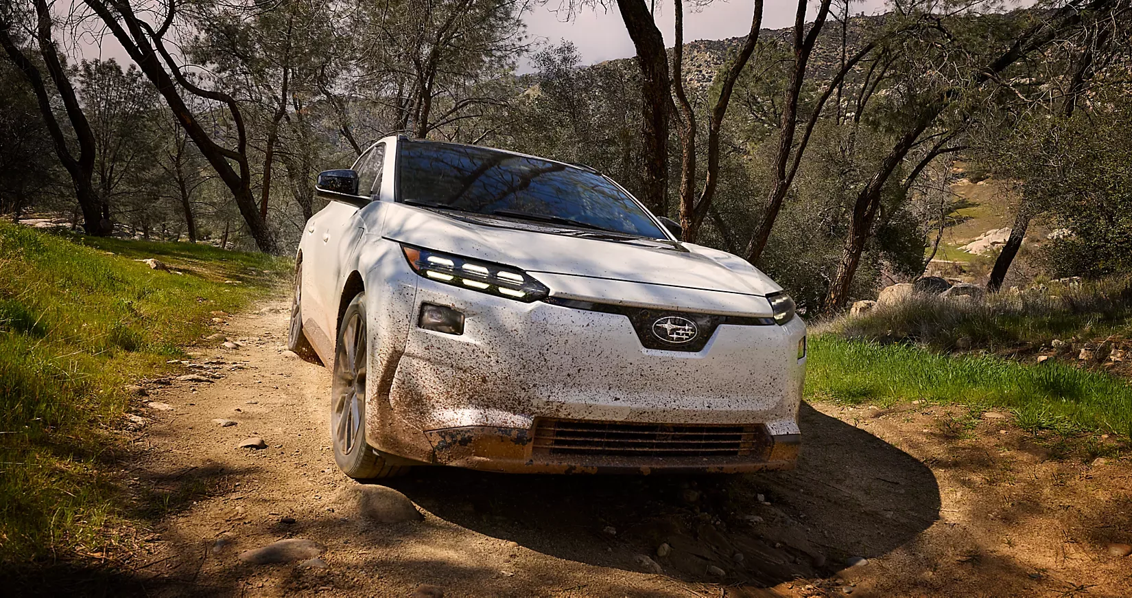 A 2026 Subaru Solterra XT parked on a rocky trail among oak trees
