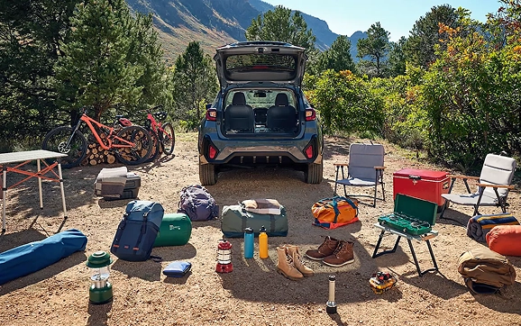 Camping and cycling gear laid out behind the open rear gate of a blue Subaru Crosstrek