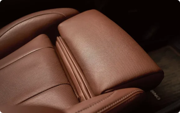 Close-up of the stitched brown leather-trimmed seat cushion and armrest