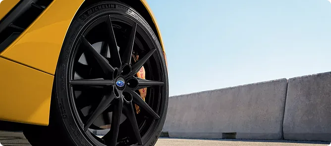 Close-up of a matte black wheel and Brembo brake on the yellow BRZ
