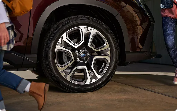 Close-up of an Ascent alloy wheel as people walk past the vehicle