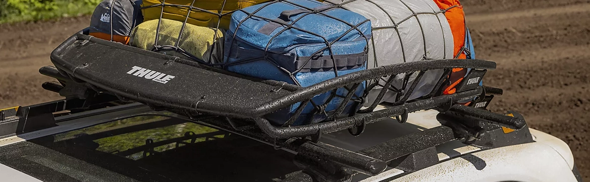 A roof-mounted cargo basket on a Subaru Forester packed with duffel bags and camping gear