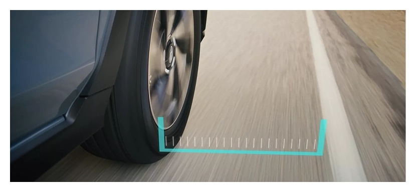 A close-up of a Subaru front wheel beside a lane marking with a teal lane-departure graphic on the road