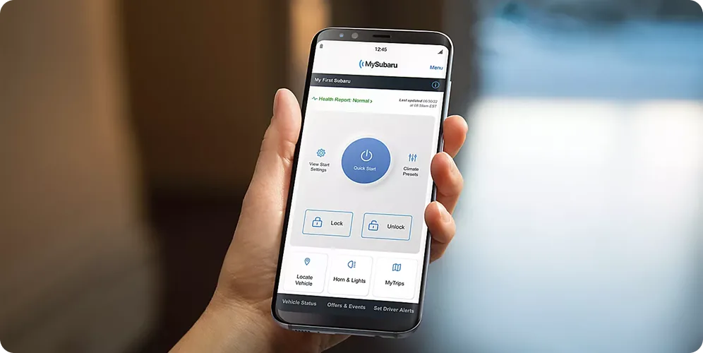 A hand holding a smartphone showing the MySubaru app remote controls