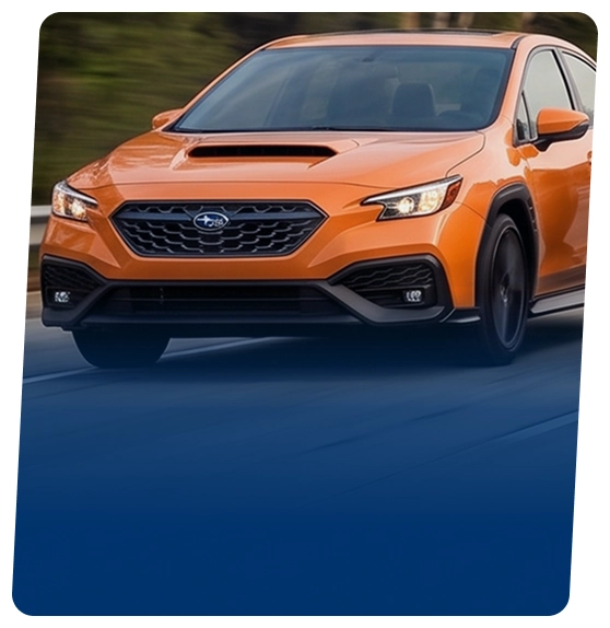 An orange Subaru WRX sedan on a city street