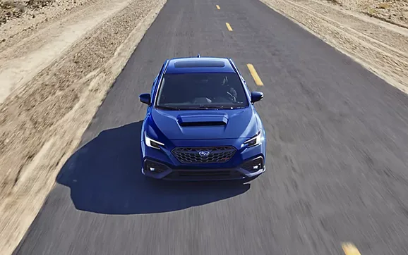 A blue Subaru WRX seen head-on along a desert highway
