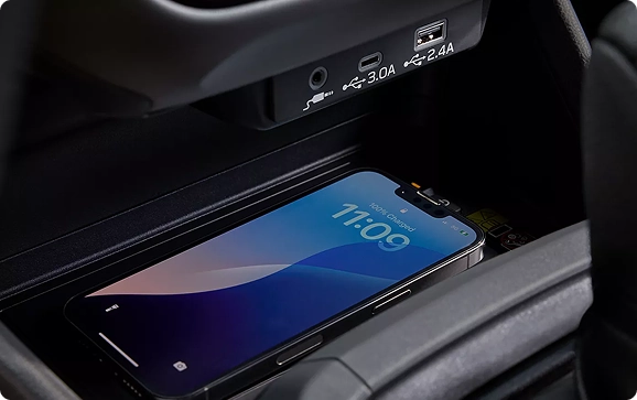 A smartphone charging on the wireless charging pad below the USB-A and USB-C ports of a Subaru Crosstrek