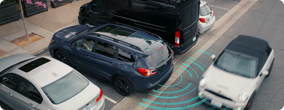 An overhead view of a dark blue Subaru SUV backing out of a parking space with teal detection waves fanning out behind it