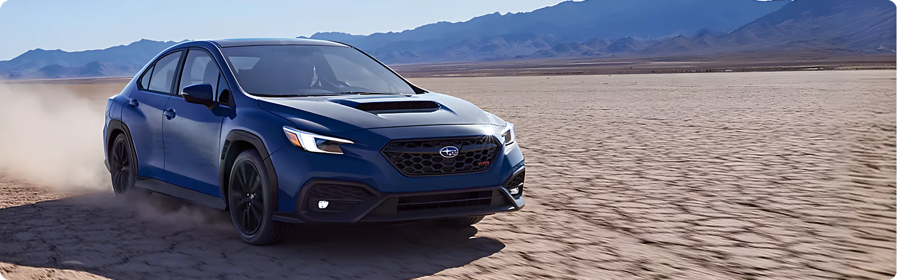 A dark blue Subaru WRX sliding across a dry lake bed