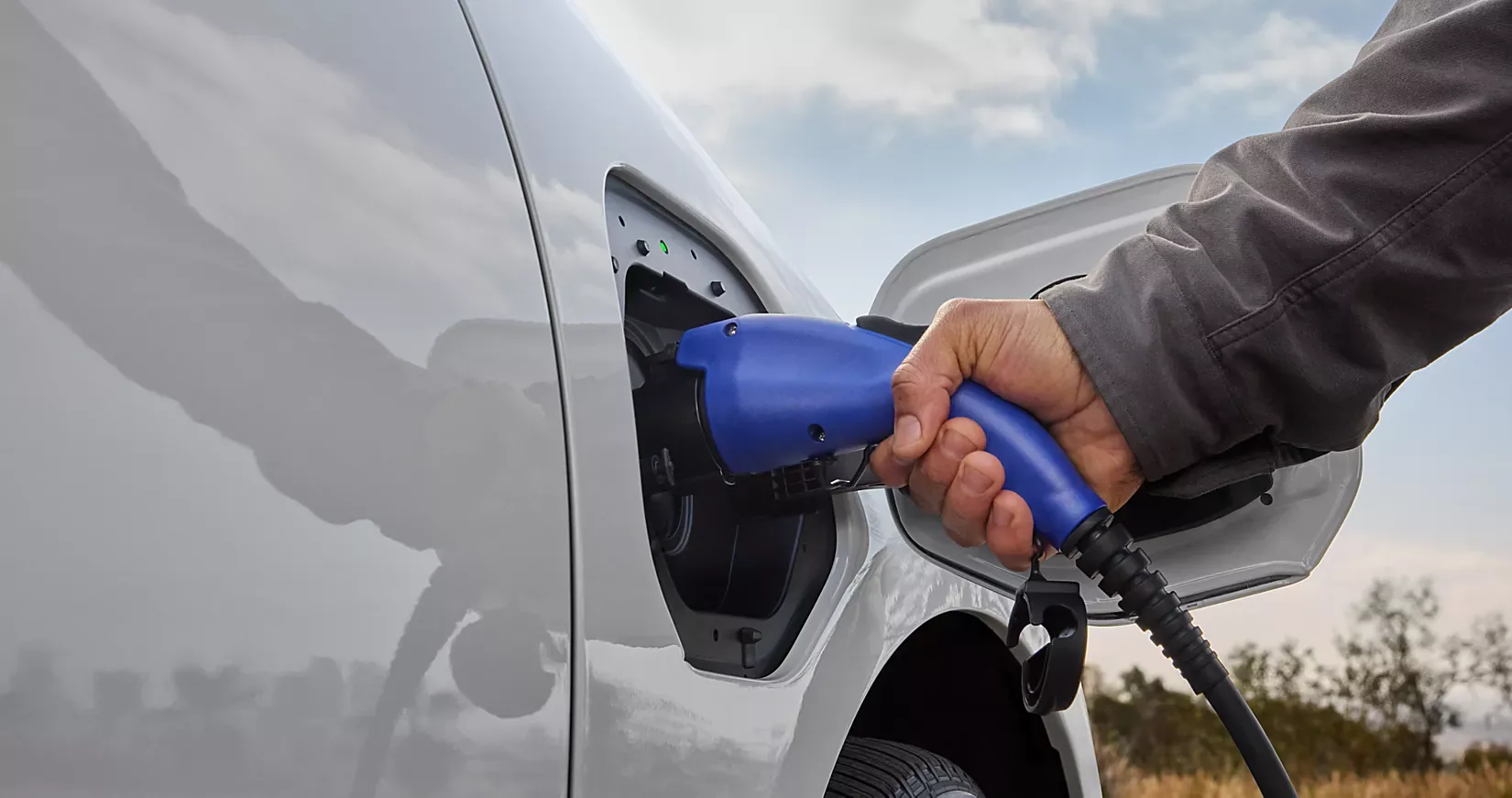 A hand plugging a charging cable into the 2026 Subaru Solterra charge port