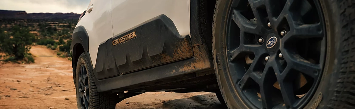 A close-up of the black wheel arch and all-terrain tire of a Subaru Crosstrek Wilderness on red rock