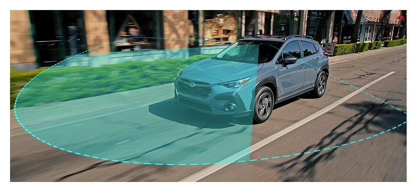 A teal Subaru Crosstrek on a city street with a green pre-collision detection zone projected ahead of it