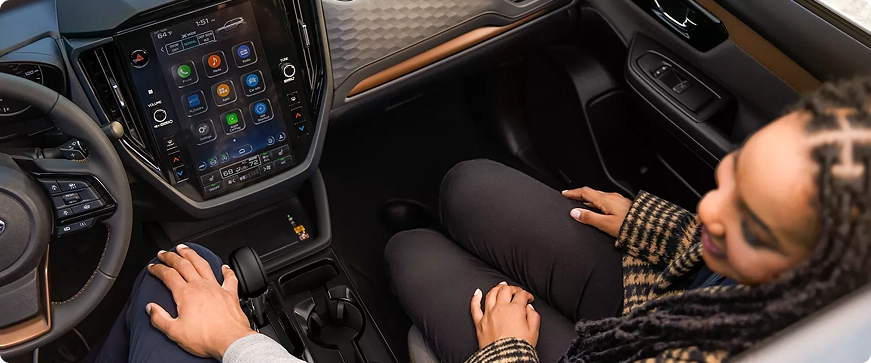 A passenger using the large vertical touchscreen in the center console of a Subaru Forester