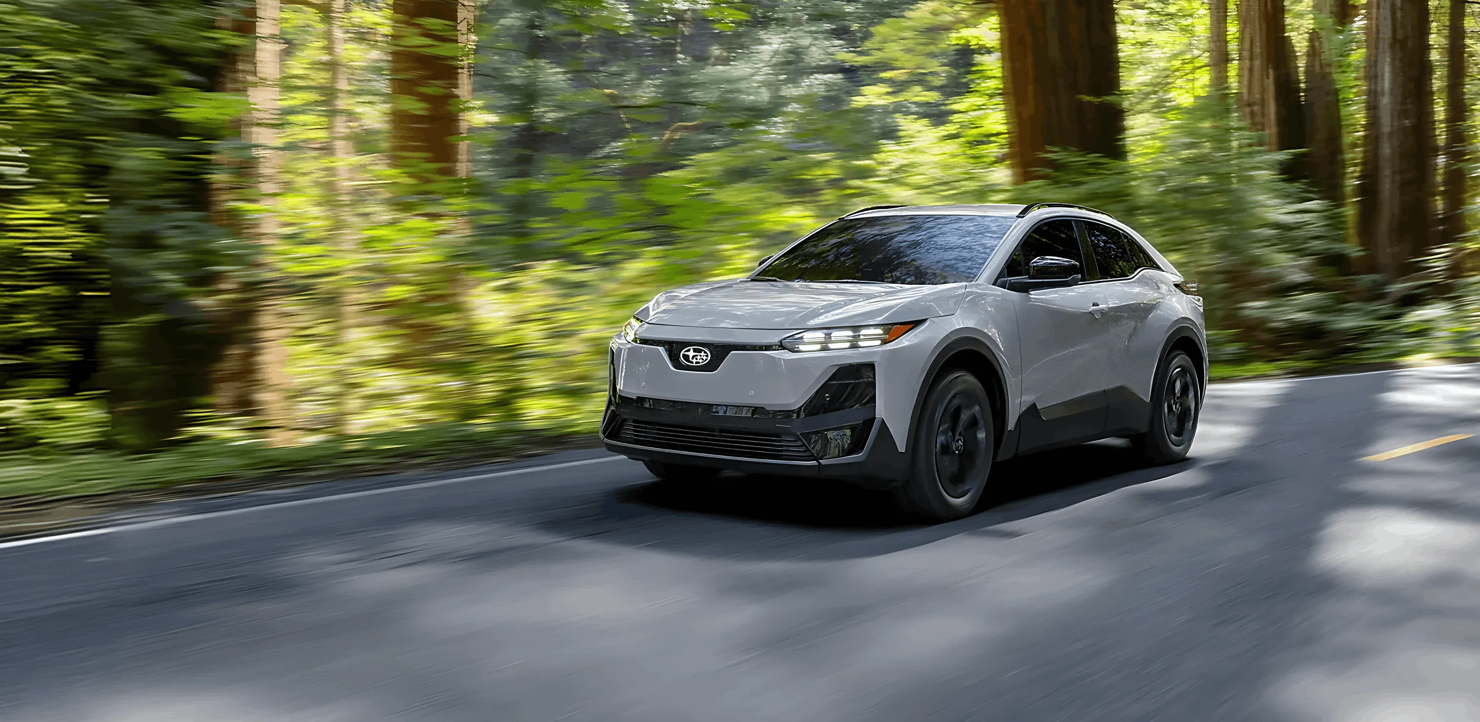 A 2026 Subaru Uncharted travelling a tree-lined road