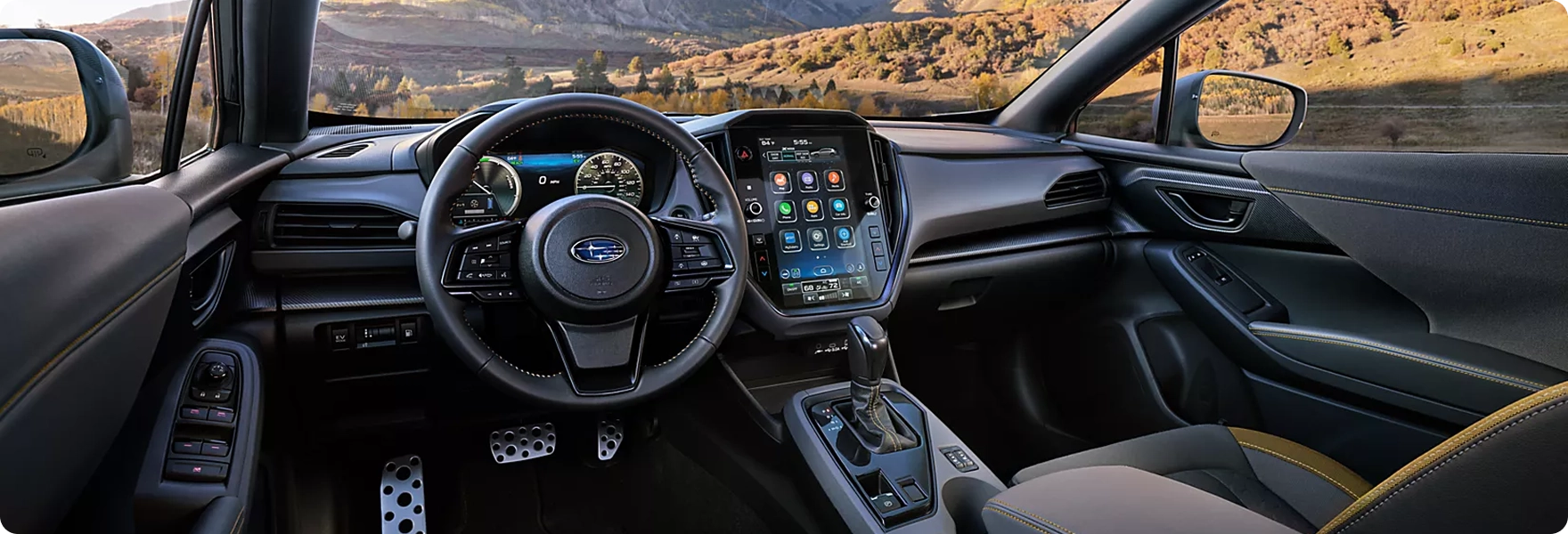 The steering wheel, digital gauges, and large vertical Subaru Multimedia touchscreen in a 2026 Subaru Crosstrek with yellow stitching