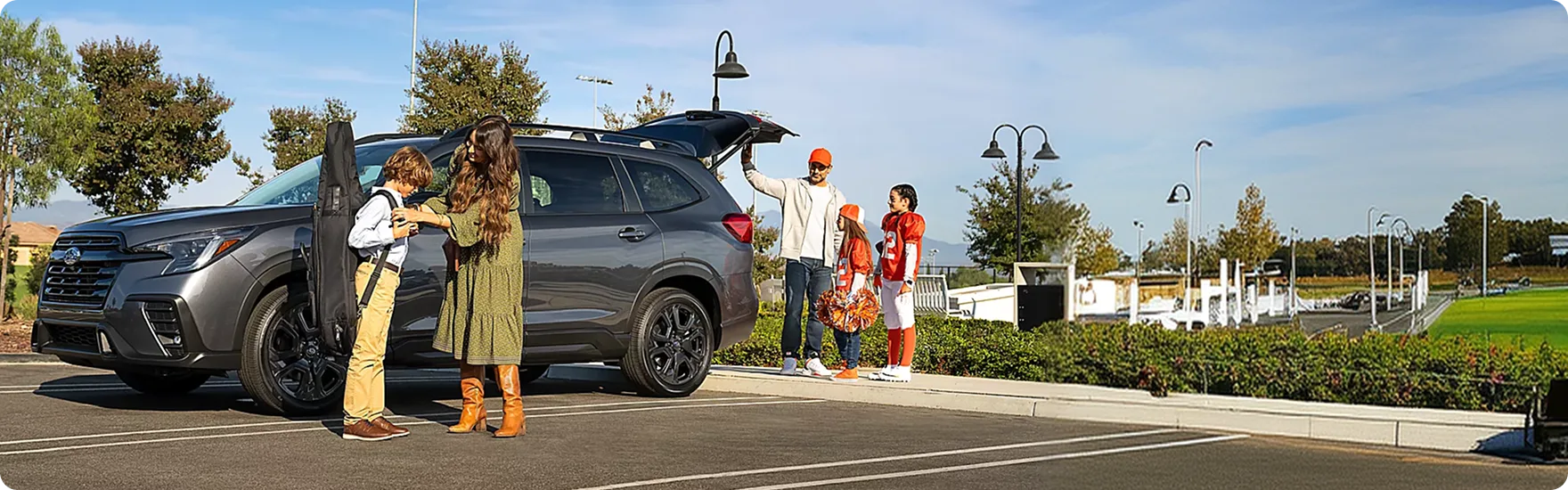 A family standing beside a grey Subaru Ascent loaded with gear