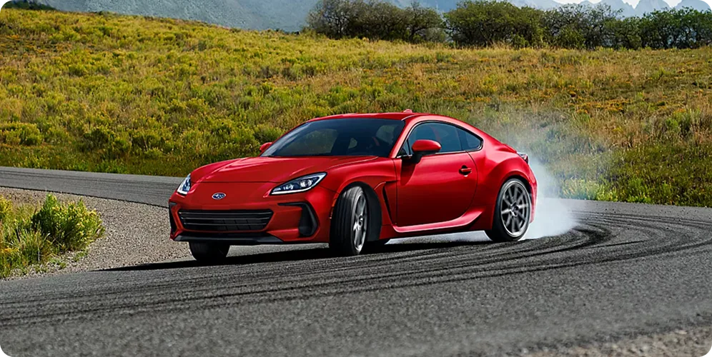A red Subaru BRZ on a green coastal road
