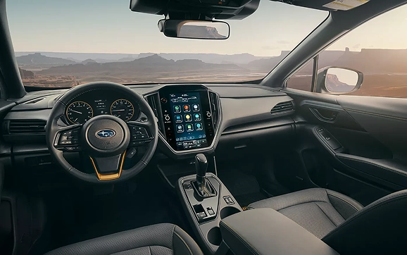 The dashboard, steering wheel, and touchscreen of a Subaru Crosstrek with a desert view ahead